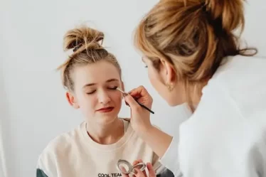 mulher maquiando uma menina loira