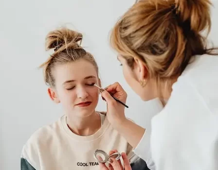 mulher maquiando uma menina loira