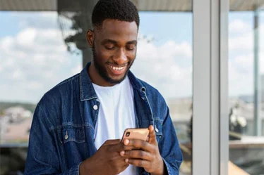 Homem mexendo no celular e sorrindo